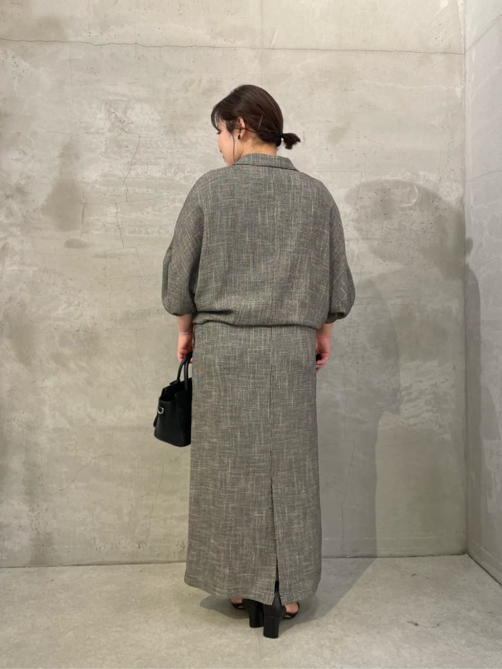 ブラック系のハンドバッグ、ベージュ系のテーラードジャケット、ベージュ系のスカートを着用したレディースの春コーディネートの3枚目の写真