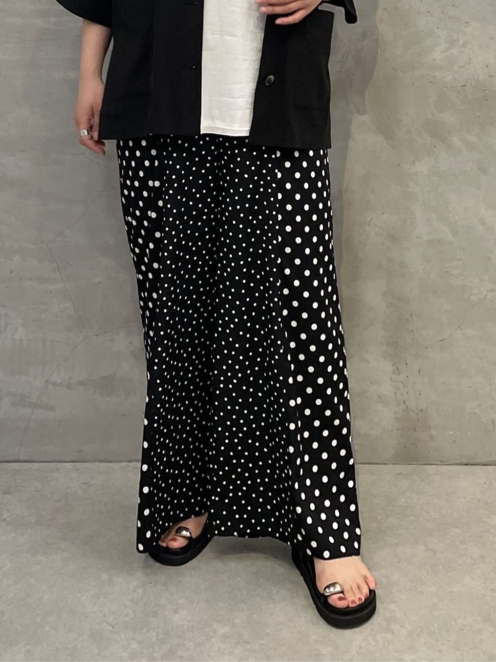 ホワイト系のタンクトップ、ブラック系のボストンバッグ、ブラック系のサンダルを着用したレディースの春コーディネートの6枚目の写真