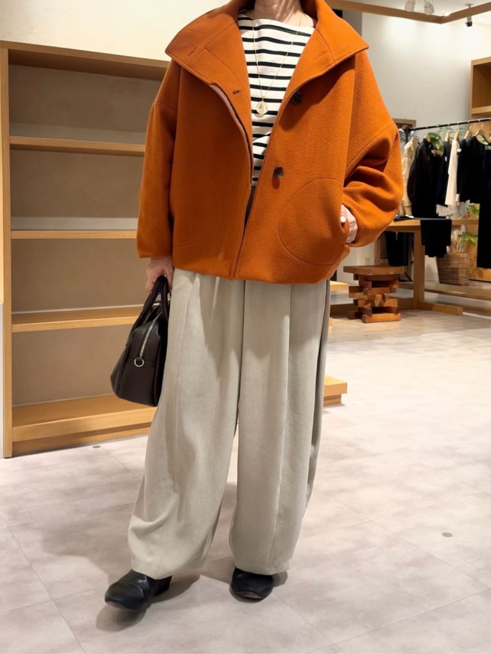 グレー系のその他パンツ、オレンジ系のその他アウターを着用したレディースの秋コーディネートの2枚目の写真