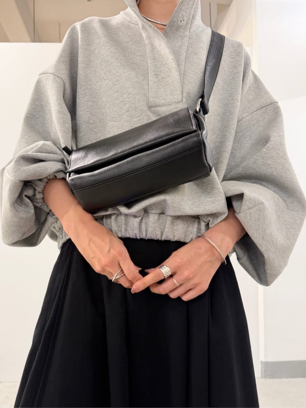 ブラック系のショルダーバッグ、ブラック系のスカート、グレー系のTシャツ/カットソーを着用したレディースの夏コーディネートの6枚目の写真