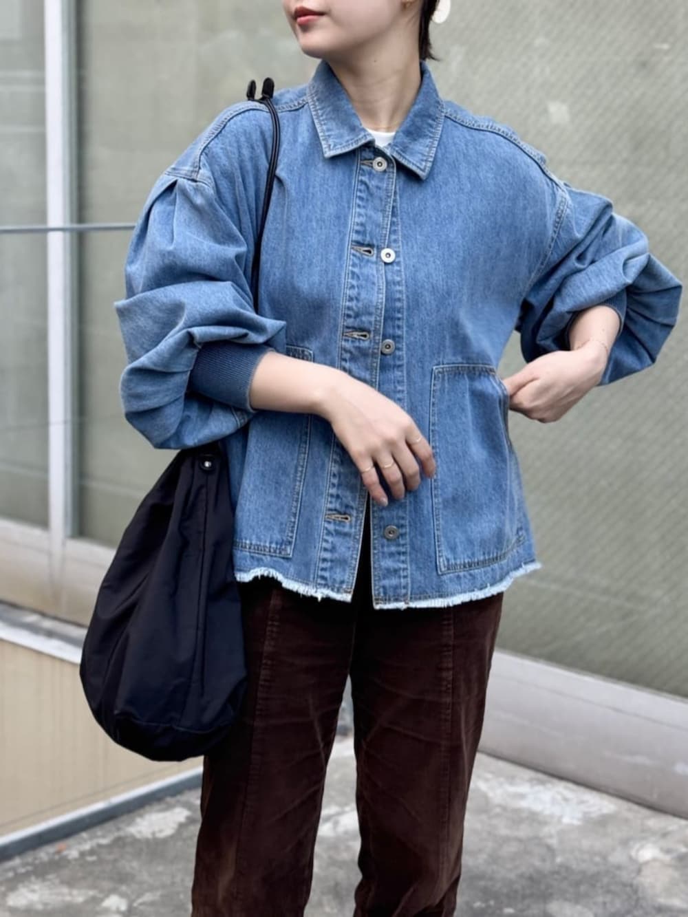 ブルー系のデニムジャケット、ブラック系のトートバッグを着用したレディースの冬コーディネートの2枚目の写真