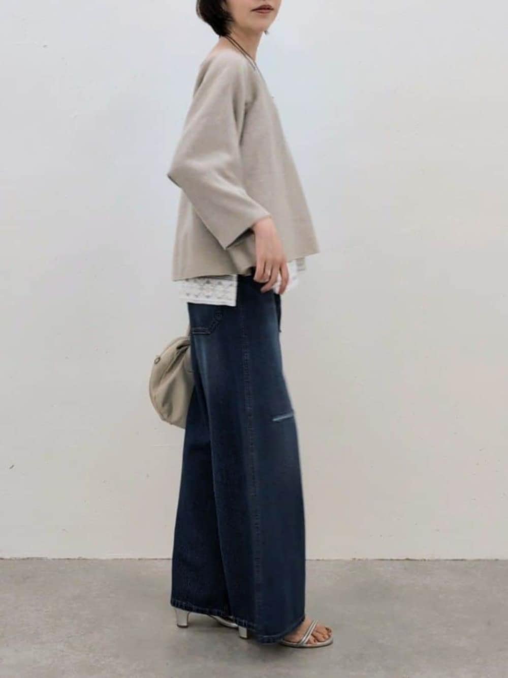 グレー系のボストンバッグ、ホワイト系のシャツ/ブラウス、ベージュ系のニット/セーターを着用したレディースの春コーディネートの3枚目の写真