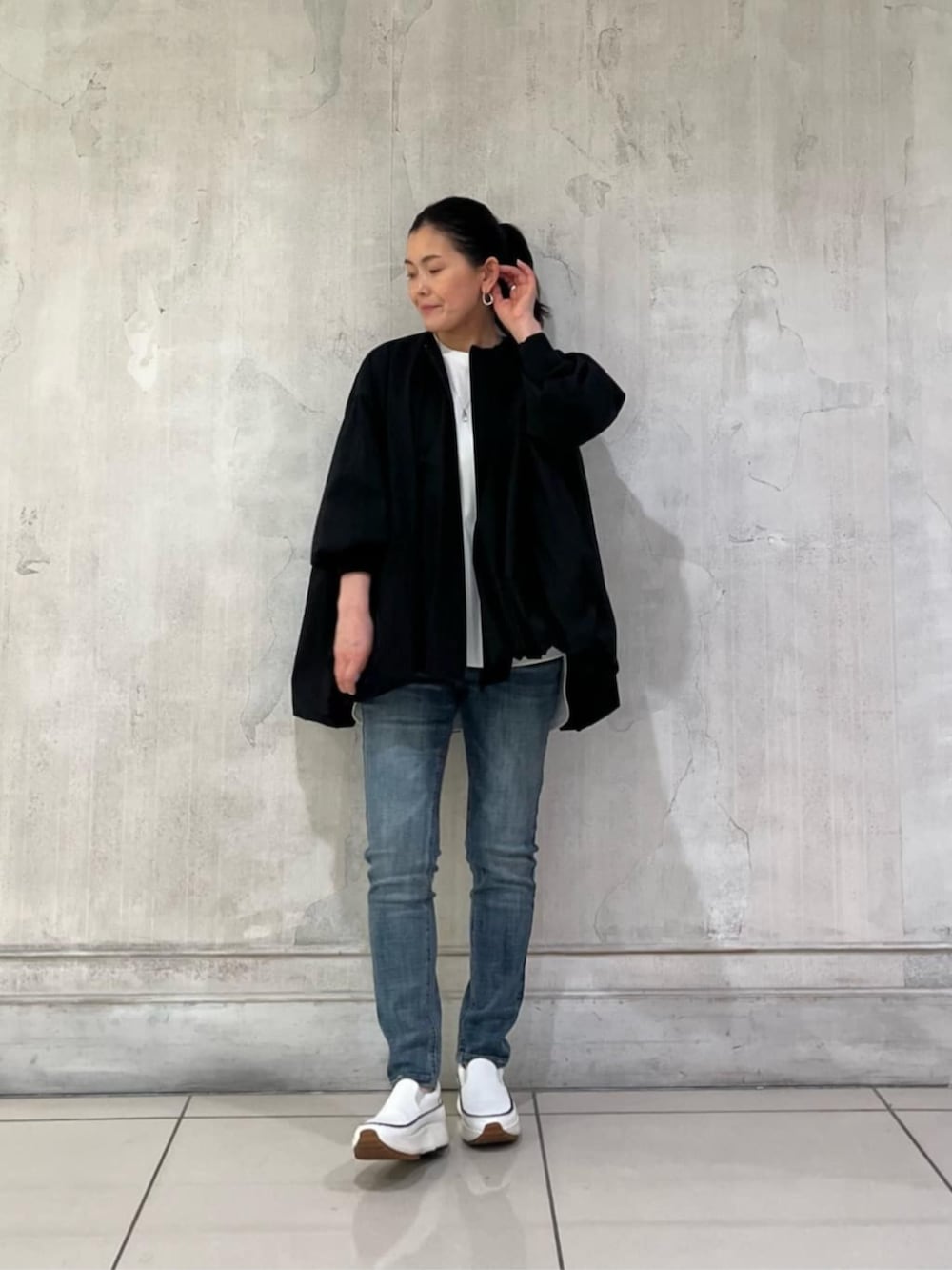 ホワイト系のスニーカー、ブルー系のデニムパンツ、ブラック系のボストンバッグを着用したレディースの冬コーディネートの3枚目の写真