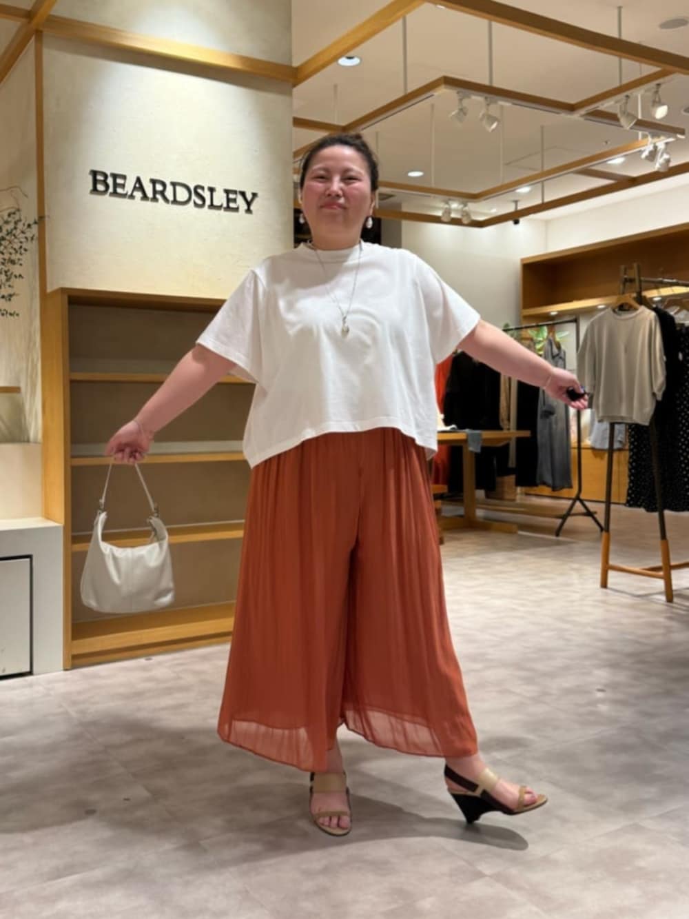 ホワイト系のトートバッグ、オレンジ系のその他パンツ、ホワイト系のTシャツ/カットソーを着用したレディースの春コーディネートの2枚目の写真