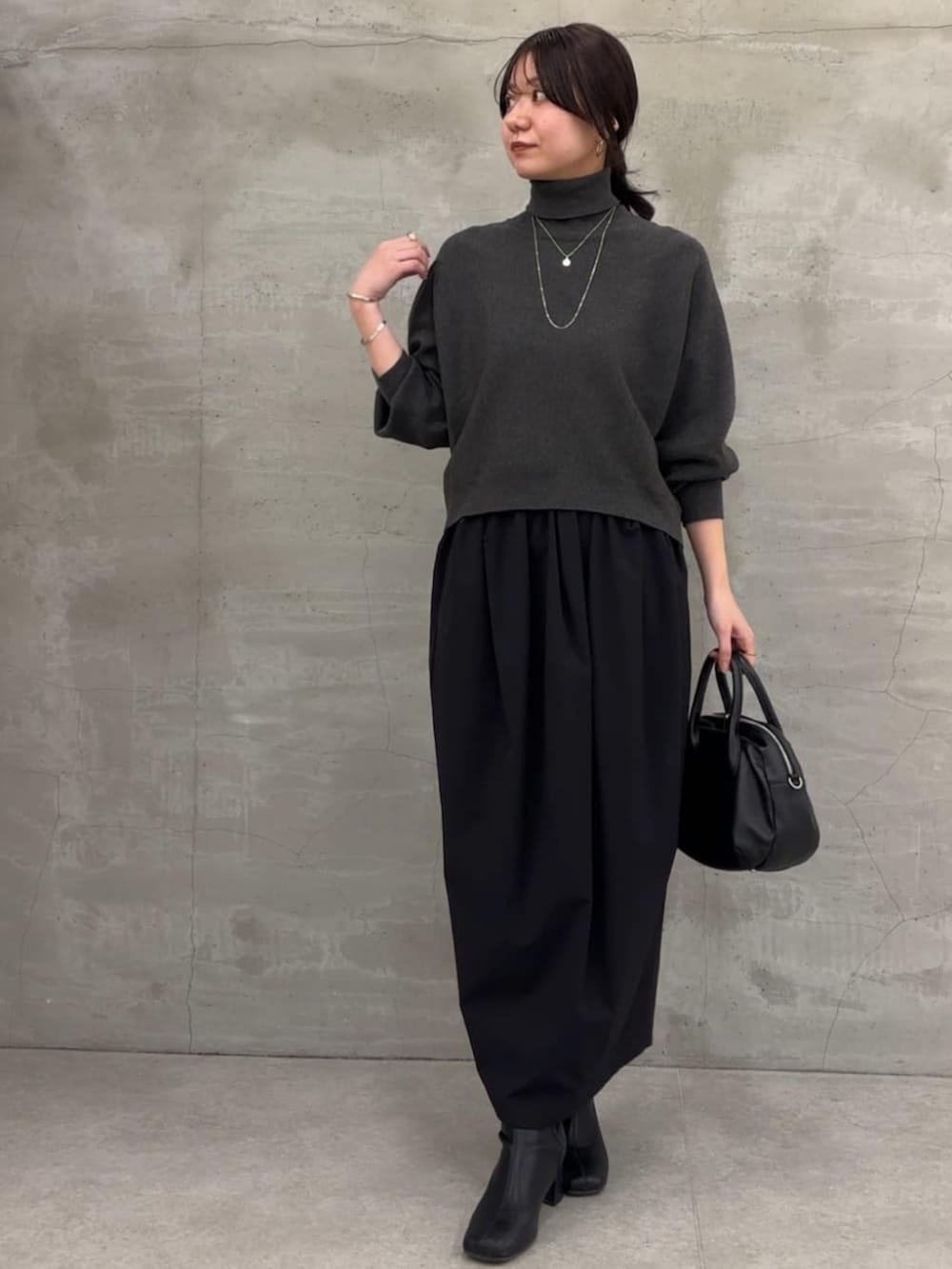 グレー系のニット/セーター、ブラック系のスカートを着用したレディースの冬コーディネートの2枚目の写真