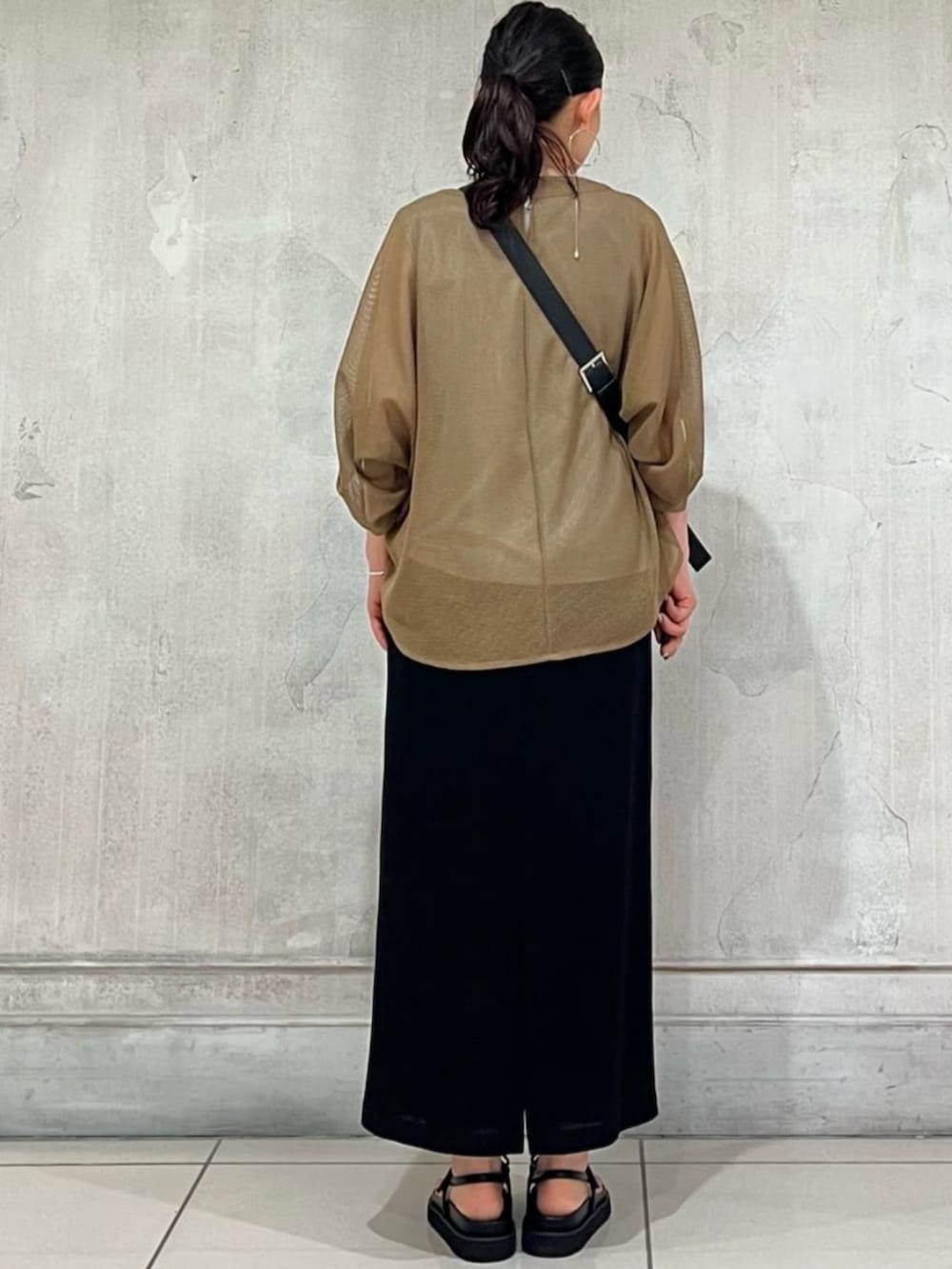 ブラック系のショルダーバッグ、ブラック系のスカート、イエロー系のTシャツ/カットソーを着用したレディースの春コーディネートの9枚目の写真