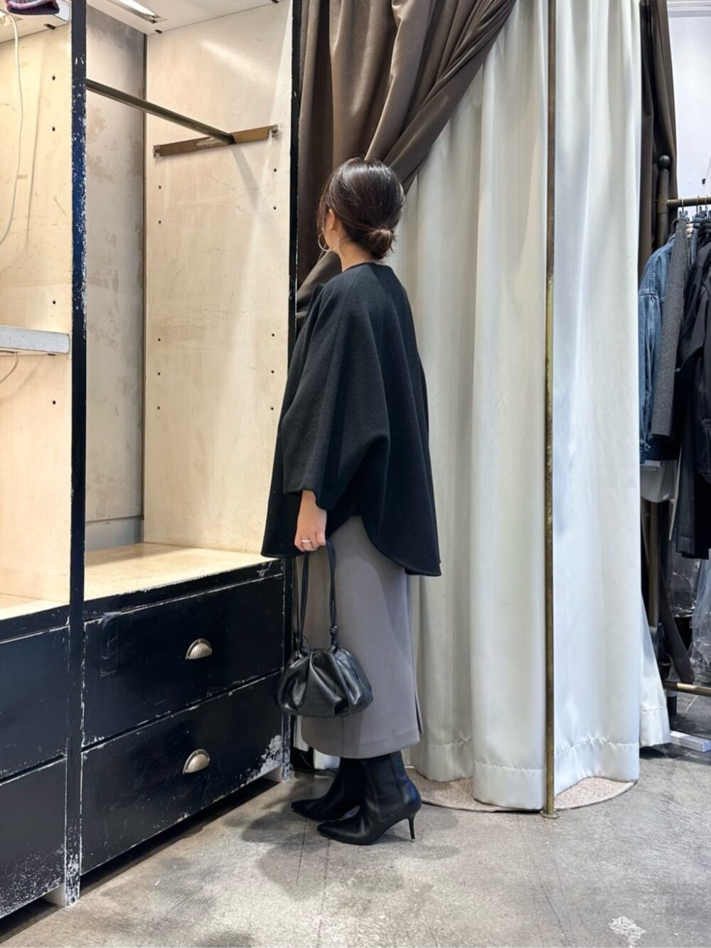 ブラック系のその他アウター、ブラウン系のスカート、ブラック系のブーツを着用したレディースの冬コーディネートの2枚目の写真