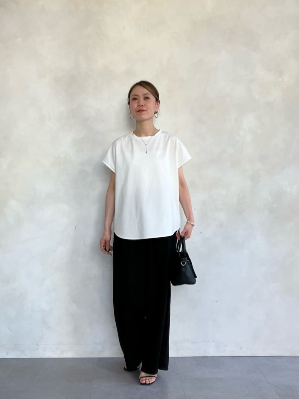 ブラック系のハンドバッグ、ホワイト系のTシャツ/カットソーを着用したレディースの春コーディネートの5枚目の写真