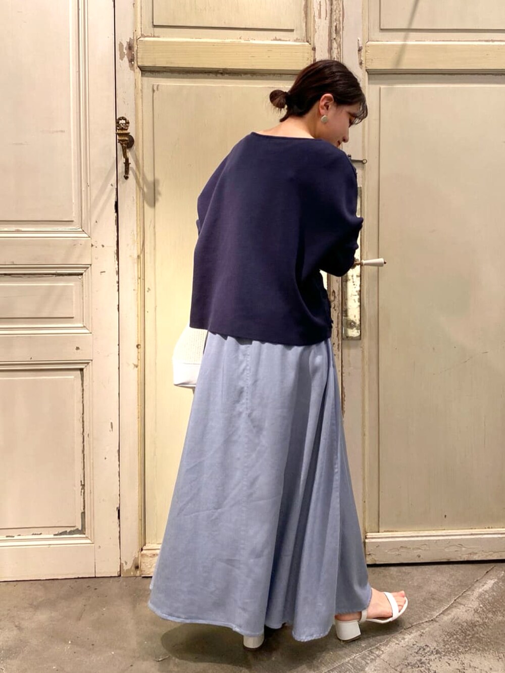 ブルー系のニット/セーター、ホワイト系のトートバッグ、ブルー系のスカートを着用したレディースの春コーディネートの2枚目の写真