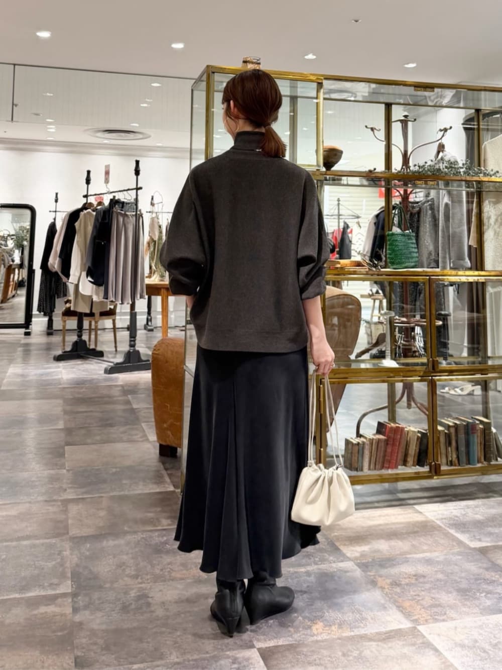 ブラック系のスカート、グレー系のニット/セーター、ベージュ系のハンドバッグを着用したレディースの冬コーディネートの2枚目の写真