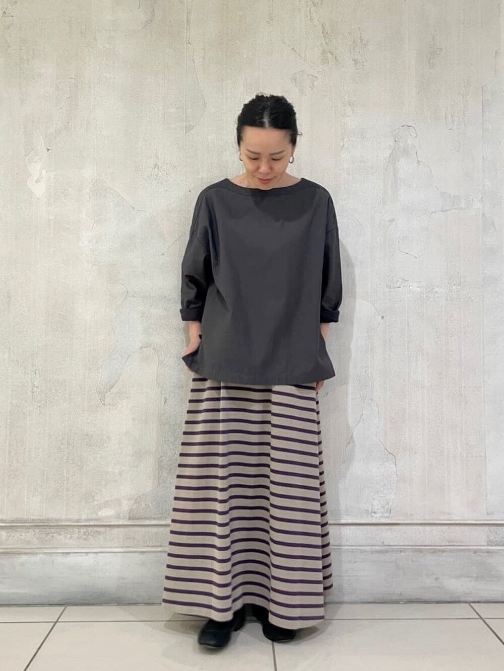 グレー系のブルゾン、グレー系のニット/セーター、ブラウン系のスカートを着用したレディースの夏コーディネートの4枚目の写真