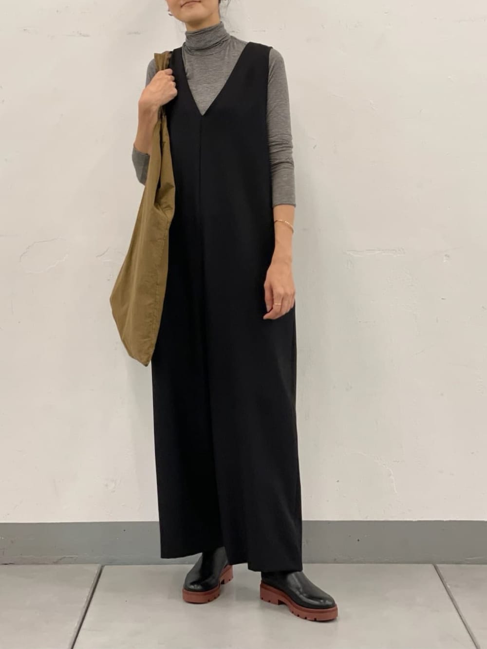 ブラック系のノーカラーコート、ベージュ系のトートバッグ、ブラック系のつなぎ/オールインワンを着用したレディースの秋コーディネートの3枚目の写真