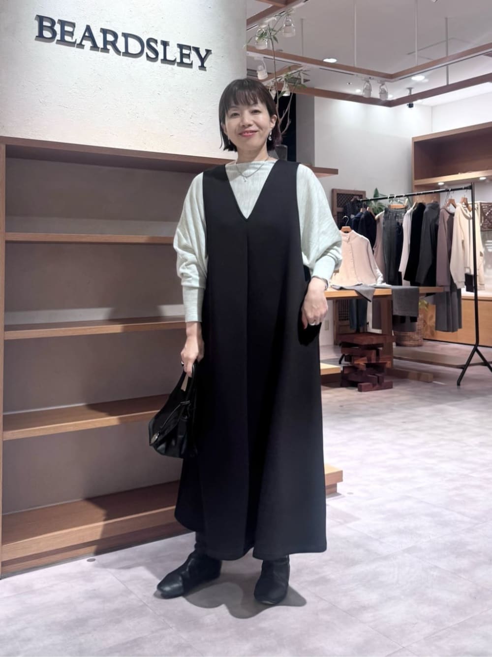 ブラック系のトートバッグ、ブラック系のジャンパースカート、ブラック系のダウンジャケット/コートを着用したレディースの冬コーディネートの7枚目の写真