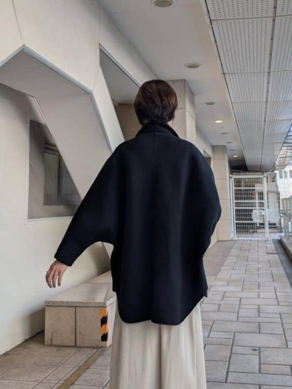 ブラック系のトートバッグ、ブラック系のその他アウター、ベージュ系のスカートを着用したレディースの夏コーディネートの5枚目の写真