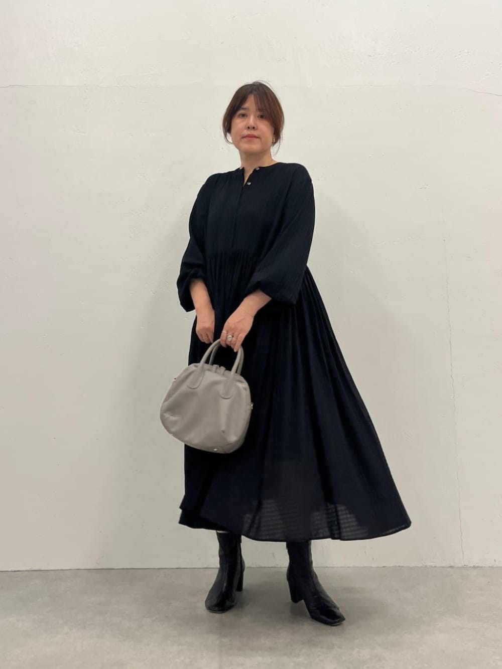 グレー系のボストンバッグ、ブラック系のワンピースを着用したレディースの夏コーディネートの4枚目の写真