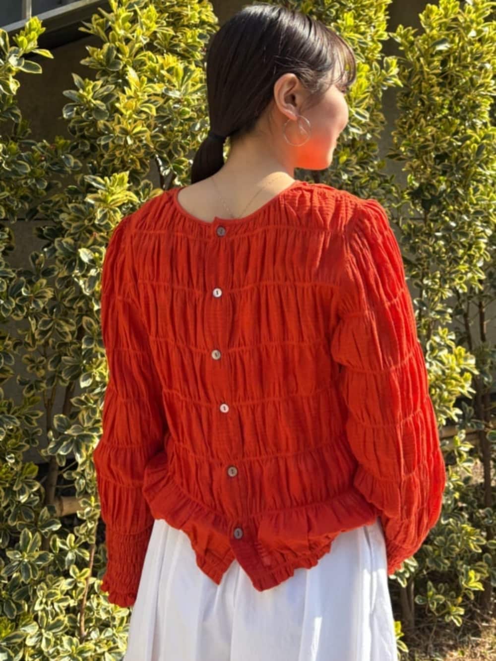 オレンジ系のシャツ/ブラウス、ホワイト系のその他パンツを着用したレディースの春コーディネートの7枚目の写真