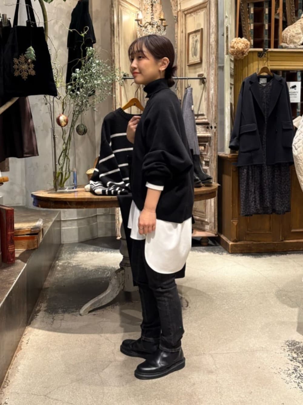 ブラック系のニット/セーター、ブラック系のデニムパンツ、ホワイト系のシャツ/ブラウスを着用したレディースの冬コーディネートの6枚目の写真