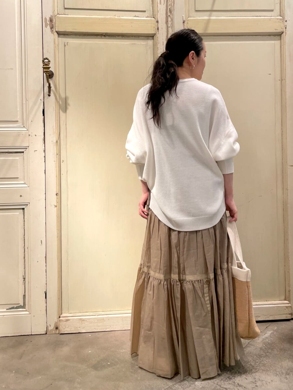 ベージュ系のスカート、ホワイト系のトートバッグ、ホワイト系のニット/セーターを着用したレディースの冬コーディネートの3枚目の写真