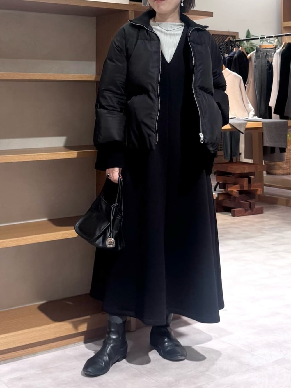 ブラック系のトートバッグ、ブラック系のジャンパースカート、ブラック系のダウンジャケット/コートを着用したレディースの冬コーディネートの3枚目の写真