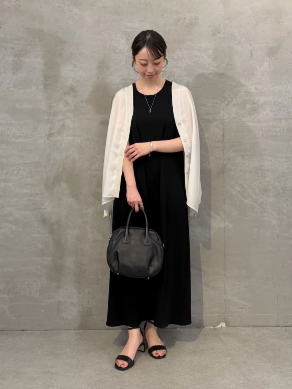 ブラック系のボストンバッグ、ホワイト系のシャツ/ブラウス、ブラック系のワンピースを着用したレディースの春コーディネートの2枚目の写真