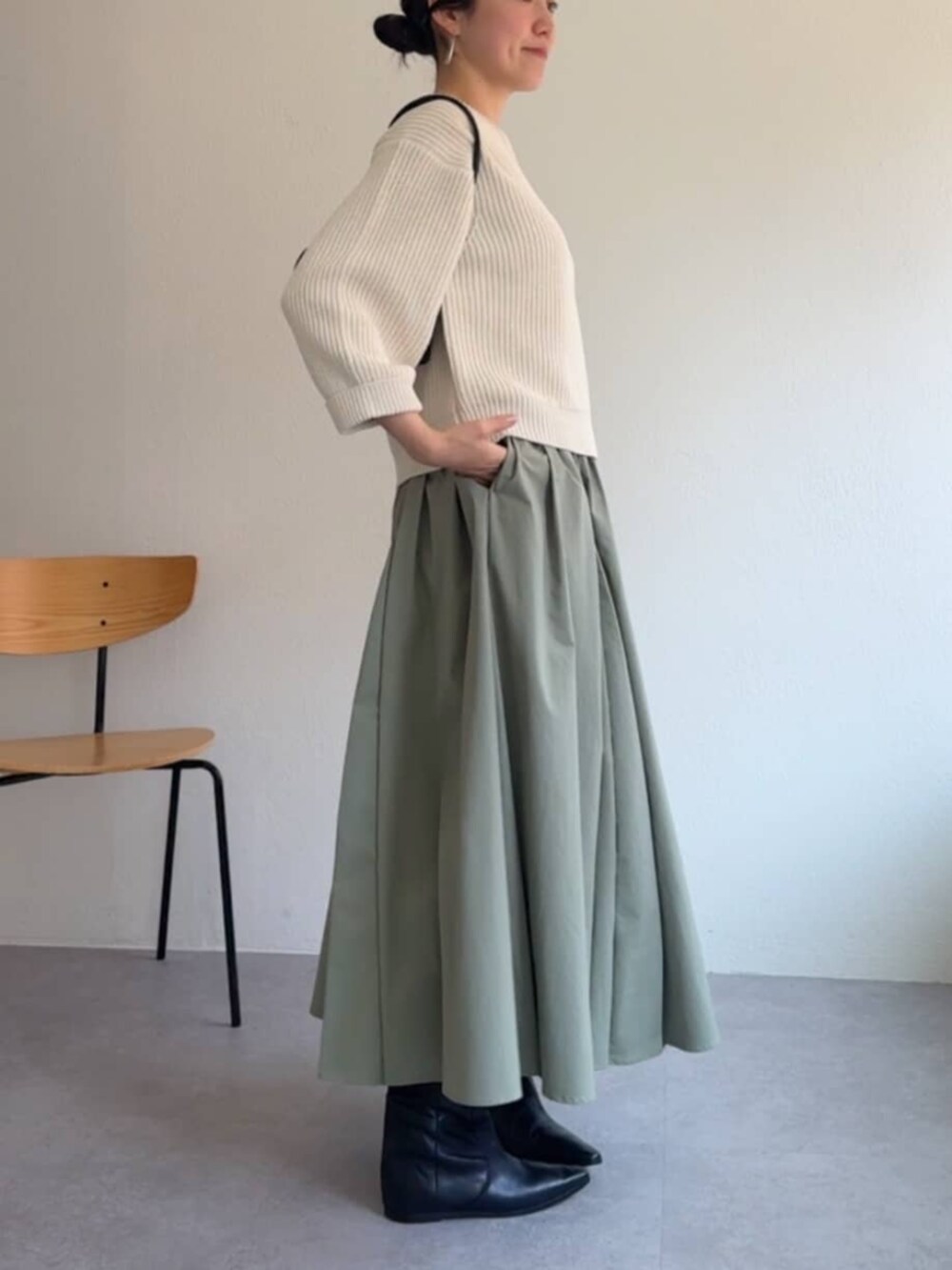 グリーン系のスカート、ホワイト系のニット/セーターを着用したレディースの冬コーディネートの3枚目の写真