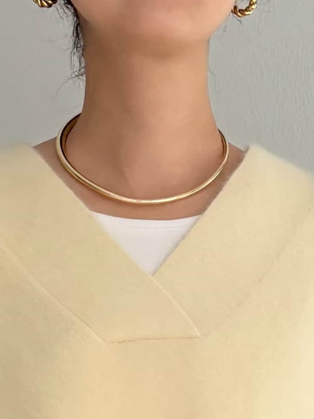 グレー系のハンドバッグ、ホワイト系のシャツ/ブラウス、イエロー系のニット/セーターを着用したレディースの秋コーディネートの4枚目の写真