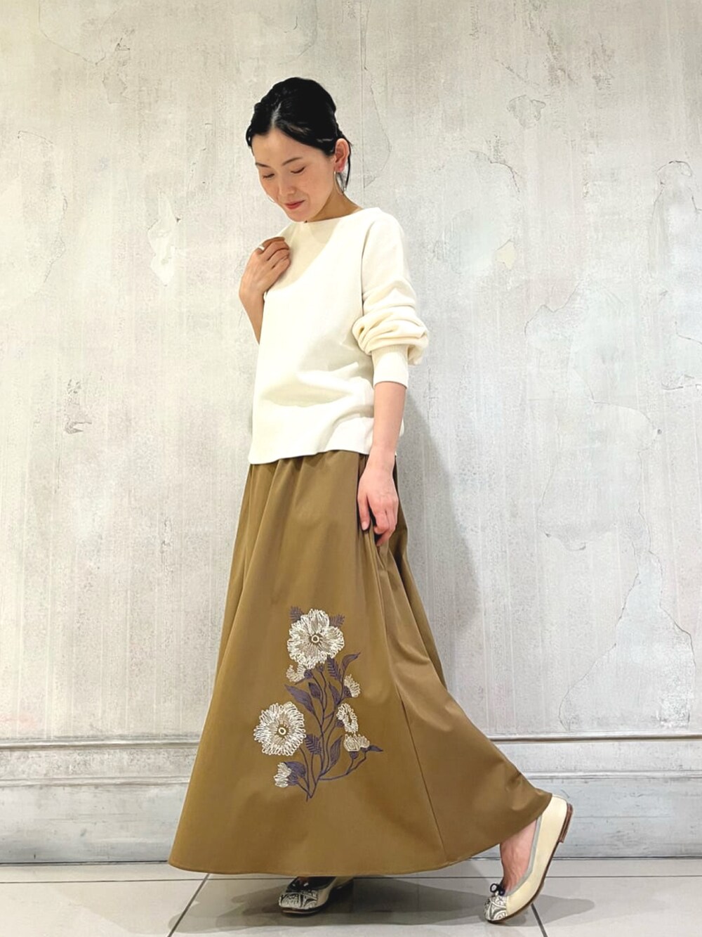 イエロー系のスカート、ホワイト系のニット/セーター、ベージュ系のバレエシューズを着用したレディースの冬コーディネートの2枚目の写真