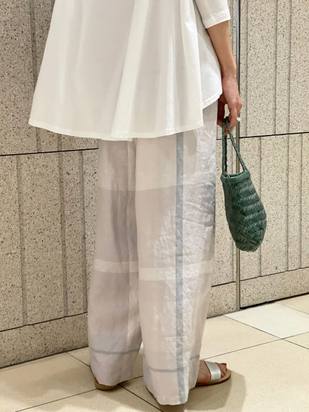 グレー系のその他パンツ、ホワイト系のTシャツ/カットソー、ホワイト系のサンダルを着用したレディースの春コーディネートの4枚目の写真