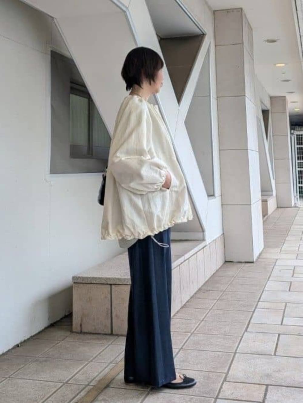 ブルー系のその他パンツ、グレー系のニット/セーター、ホワイト系のノーカラージャケットを着用したレディースの冬コーディネートの2枚目の写真