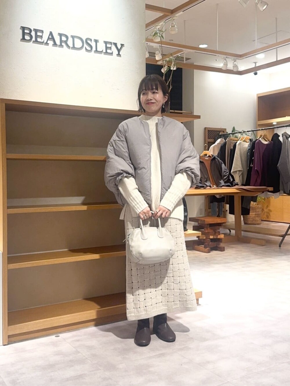 グレー系のボストンバッグ、ベージュ系のスカート、ブラウン系のダウンジャケット/コートを着用したレディースの冬コーディネートの4枚目の写真