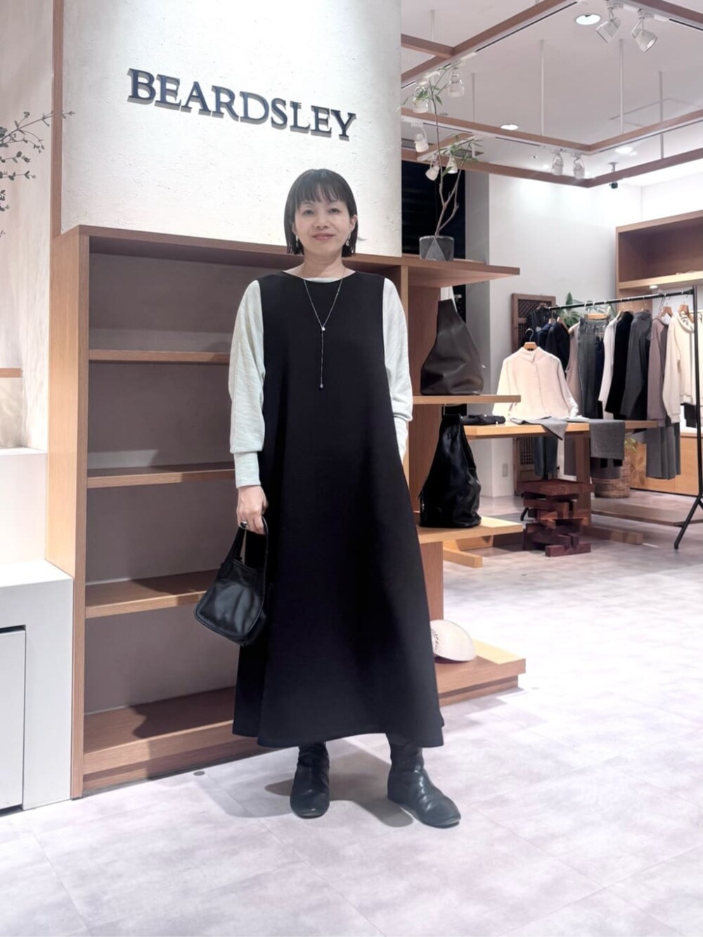 ブラック系のトートバッグ、ブラック系のジャンパースカート、ブラック系のダウンジャケット/コートを着用したレディースの冬コーディネートの8枚目の写真