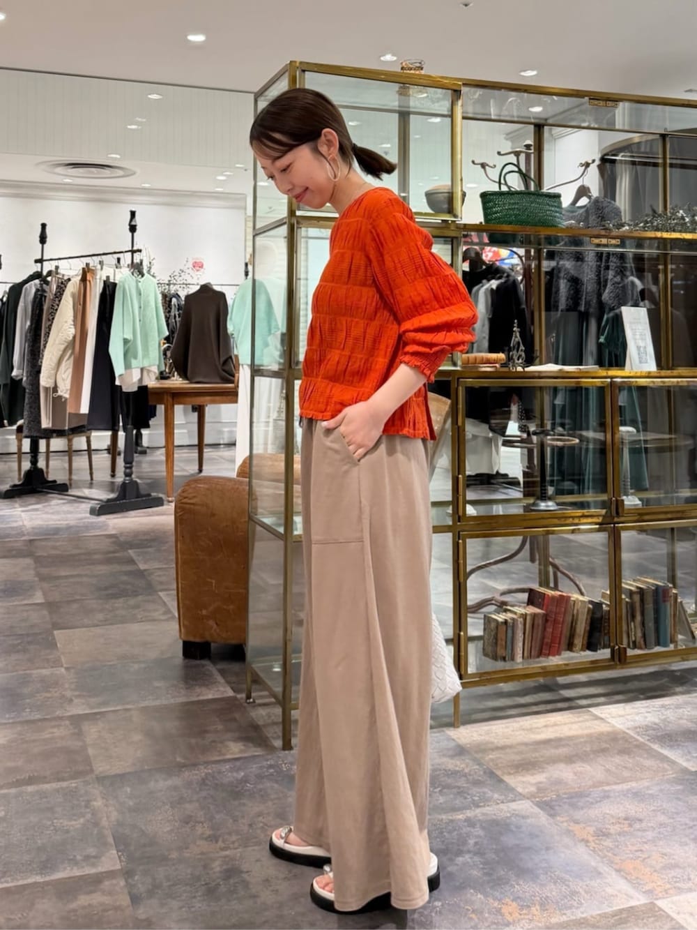 オレンジ系のシャツ/ブラウス、ベージュ系のその他パンツ、ホワイト系のサンダルを着用したレディースの春コーディネートの2枚目の写真