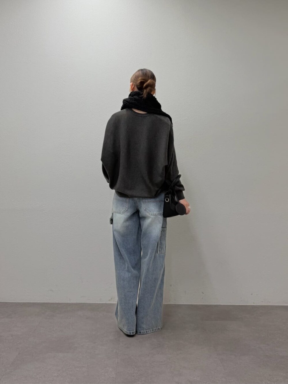 グレー系のニット/セーター、ブルー系のデニムパンツ、ブラック系のマフラーを着用したレディースの秋コーディネートの5枚目の写真