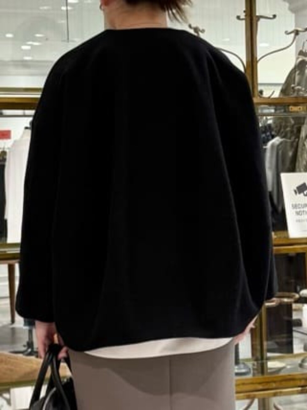 ブラウン系のスカート、ブラック系のノーカラーコートを着用したレディースの冬コーディネートの8枚目の写真