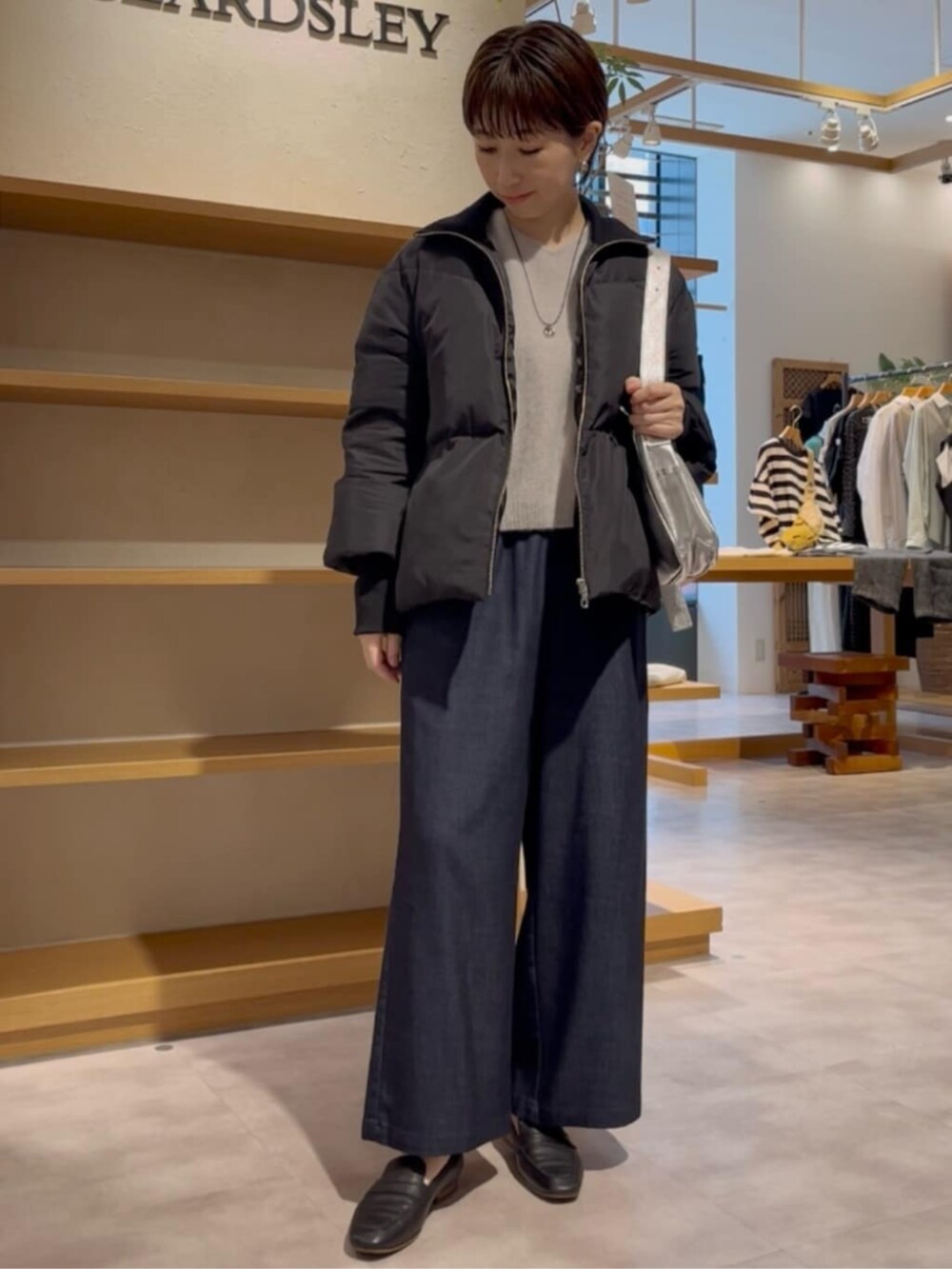 ブルー系のその他パンツ、グレー系のニット/セーター、ブラック系のダウンジャケット/コートを着用したレディースの冬コーディネートの3枚目の写真