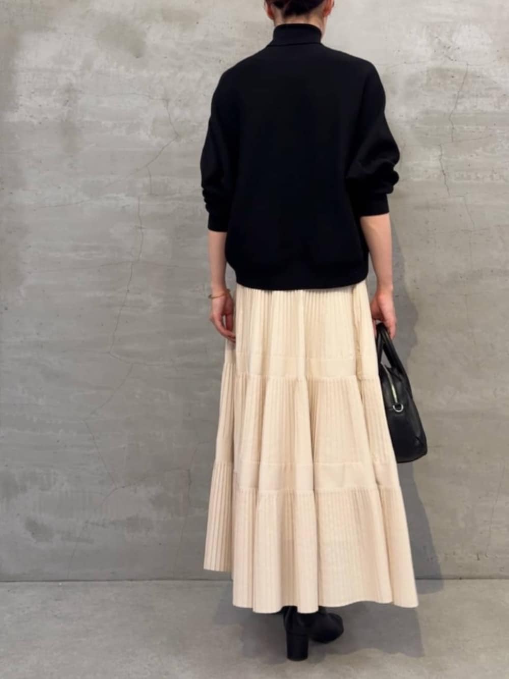 ホワイト系のスカート、ブラック系のボストンバッグ、ブラック系のニット/セーターを着用したレディースの冬コーディネートの5枚目の写真