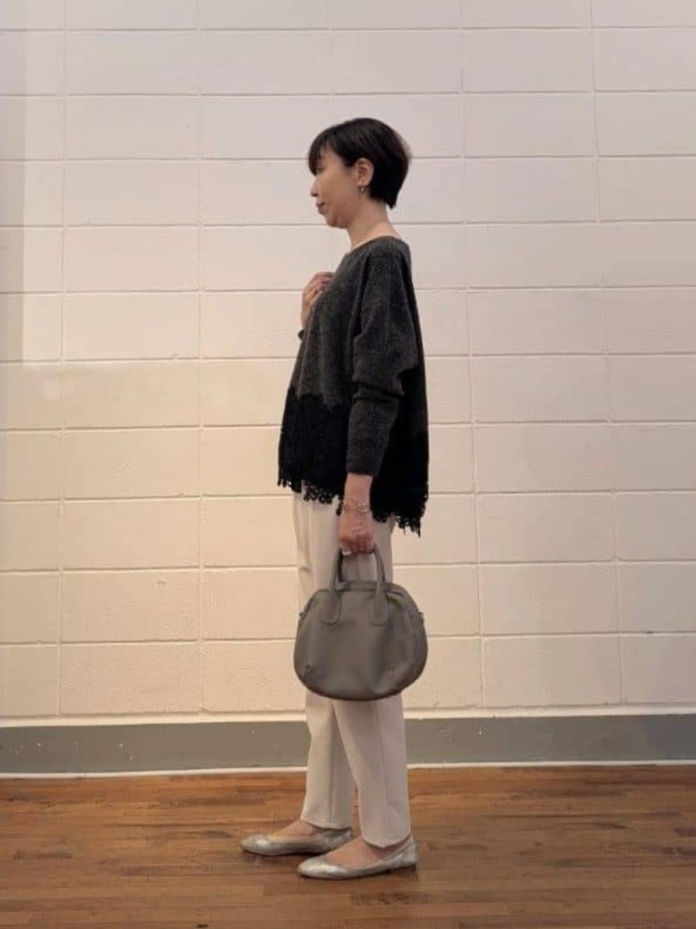 グレー系のトートバッグ、グレー系のニット/セーター、ホワイト系のその他パンツを着用したレディースの秋コーディネートの3枚目の写真