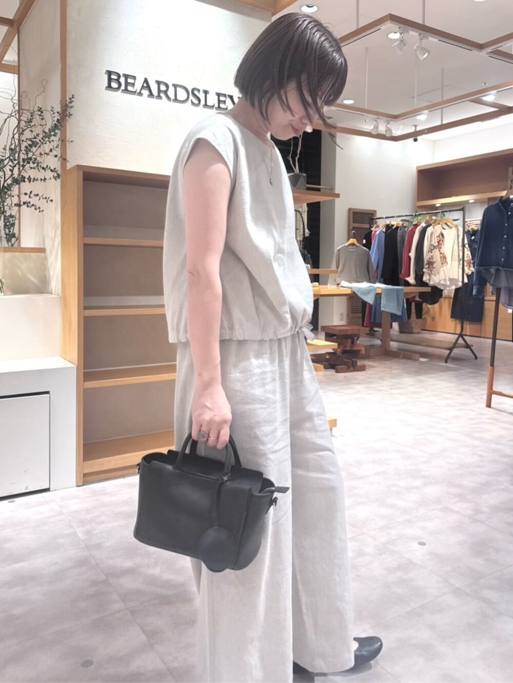 ブラック系のハンドバッグ、ベージュ系のシャツ/ブラウス、ベージュ系のその他パンツを着用したレディースの春コーディネートの3枚目の写真