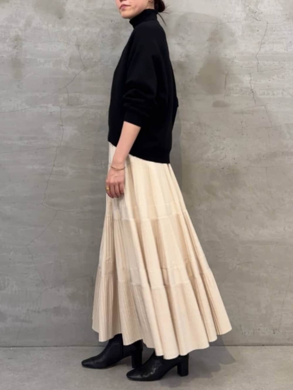 ホワイト系のスカート、ブラック系のボストンバッグ、ブラック系のニット/セーターを着用したレディースの冬コーディネートの2枚目の写真