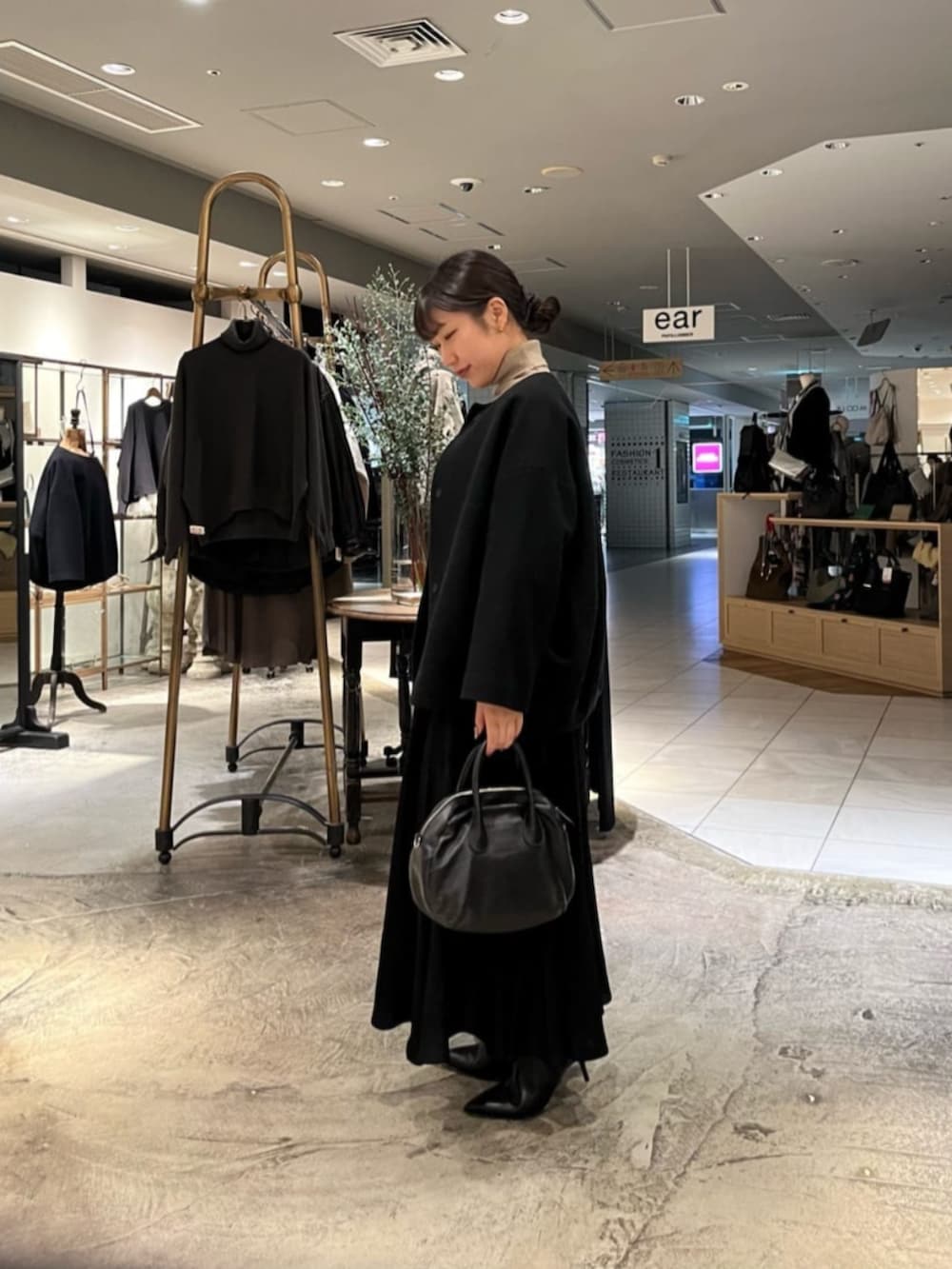 ブラック系のボストンバッグ、ブラック系のノーカラーコートを着用したレディースの冬コーディネートの3枚目の写真