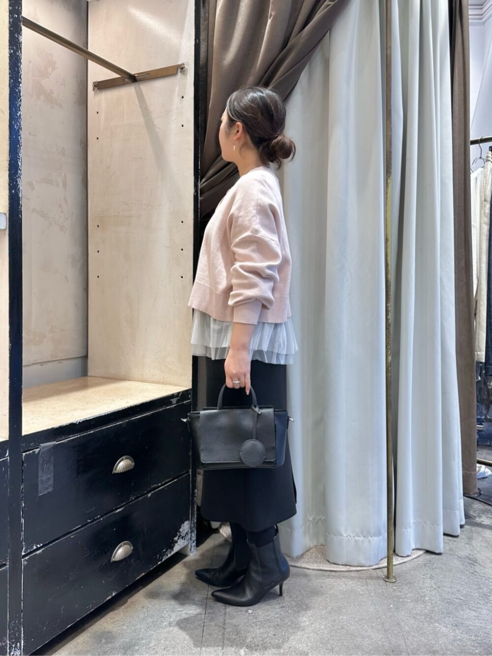 ブラック系のスカート、ブラック系のブーツ、ホワイト系のタンクトップを着用したレディースの冬コーディネートの4枚目の写真