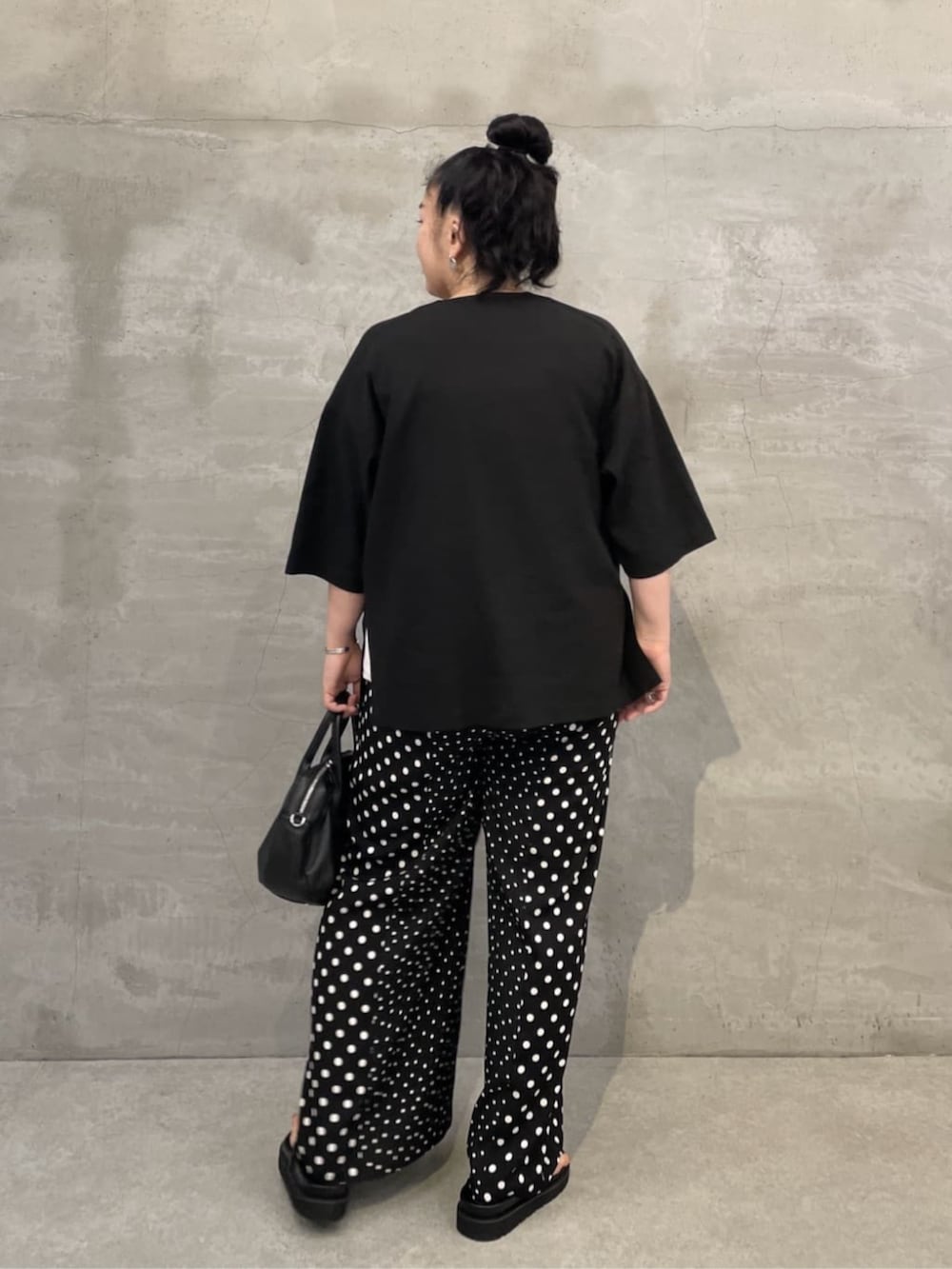 ホワイト系のタンクトップ、ブラック系のボストンバッグ、ブラック系のサンダルを着用したレディースの春コーディネートの3枚目の写真