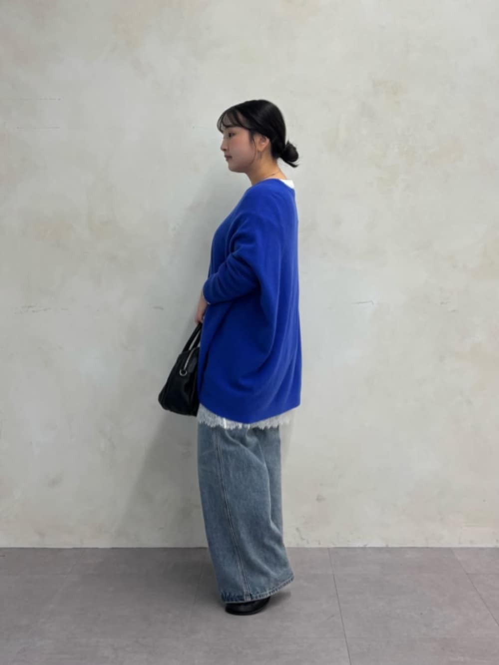 ブルー系のデニムパンツ、ブルー系のニット/セーター、ホワイト系のTシャツ/カットソーを着用したレディースの秋コーディネートの4枚目の写真