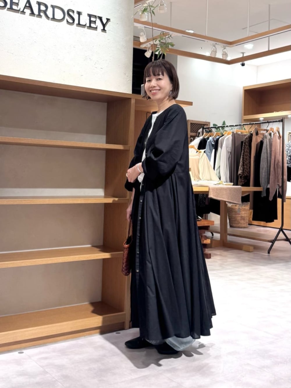 ブルー系のデニムパンツ、イエロー系のトートバッグ、ブラック系のワンピースを着用したレディースの冬コーディネートの6枚目の写真