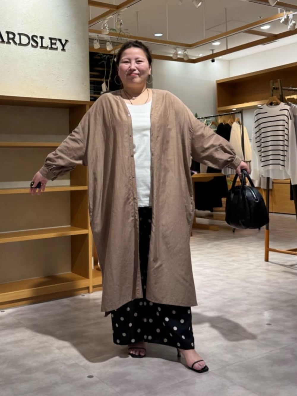 ブラック系のボストンバッグ、ベージュ系のワンピース、ブラック系のその他パンツを着用したレディースの冬コーディネートの6枚目の写真