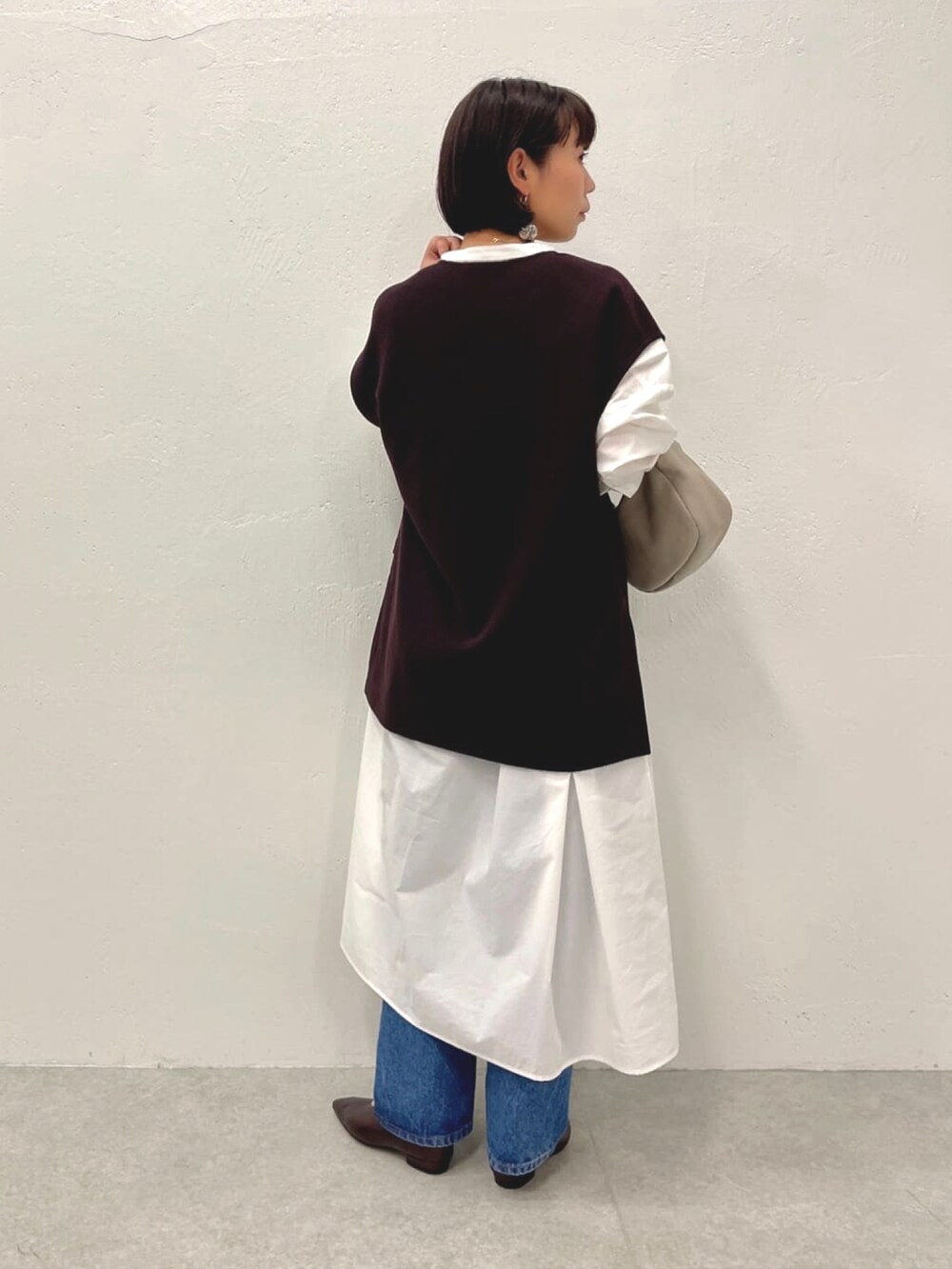 ブラウン系のTシャツ/カットソー、ホワイト系のワンピース、ブルー系のデニムパンツを着用したレディースの秋コーディネートの3枚目の写真