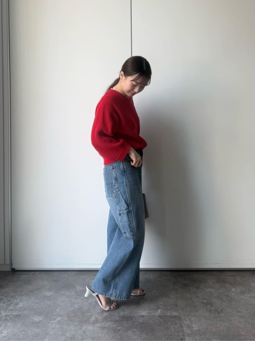 レッド系のニット/セーター、グレー系のトートバッグを着用したレディースの冬コーディネートの2枚目の写真