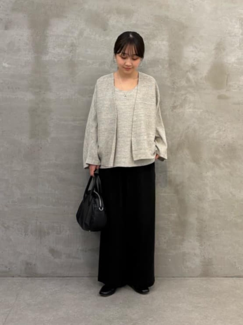 ブラック系のボストンバッグ、グレー系のニット/セーター、グレー系のカーディガン/ボレロを着用したレディースの春コーディネートの4枚目の写真