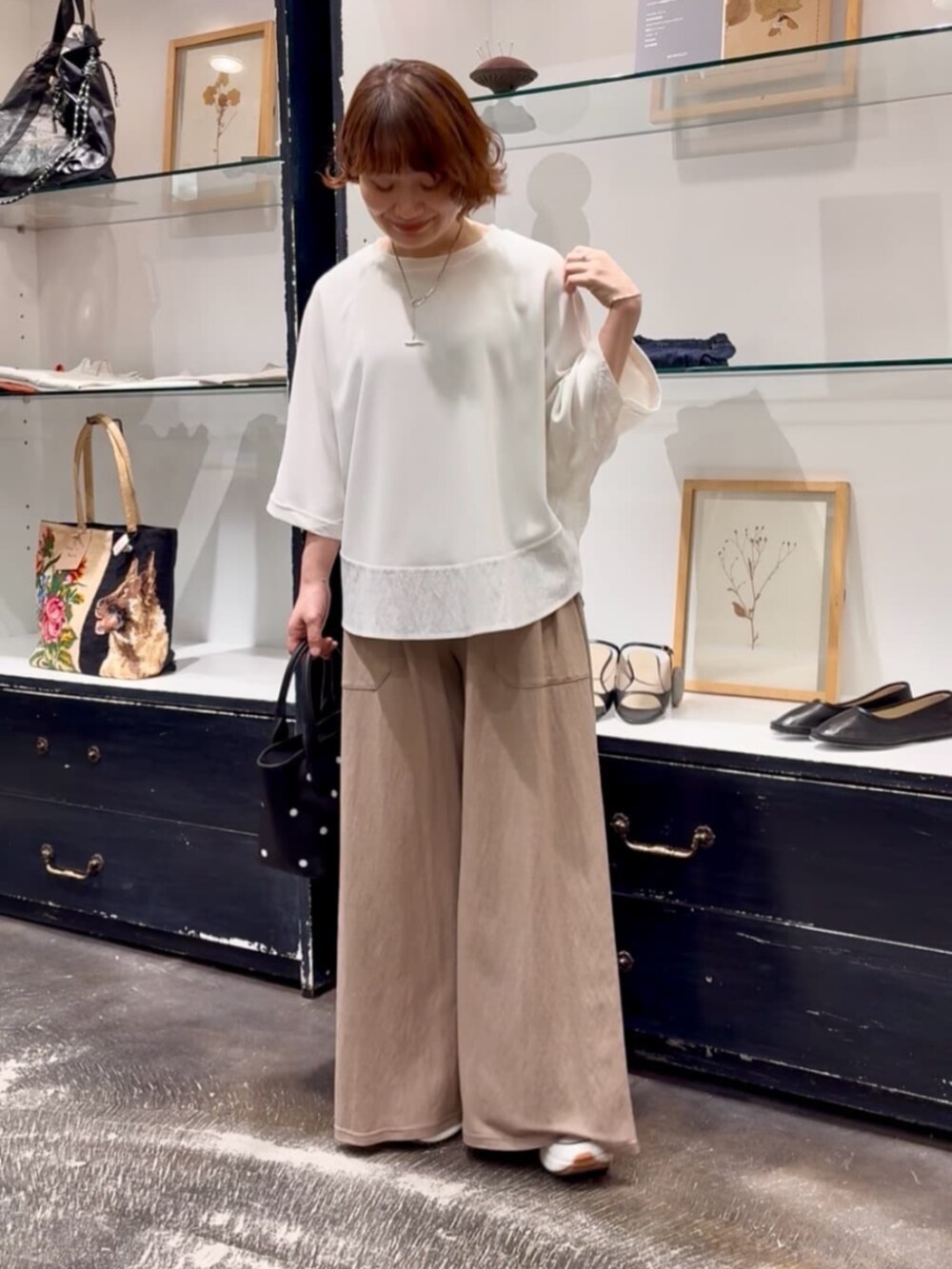 ベージュ系のその他パンツ、ブラック系のトートバッグ、ホワイト系のTシャツ/カットソーを着用したレディースの春コーディネートの3枚目の写真