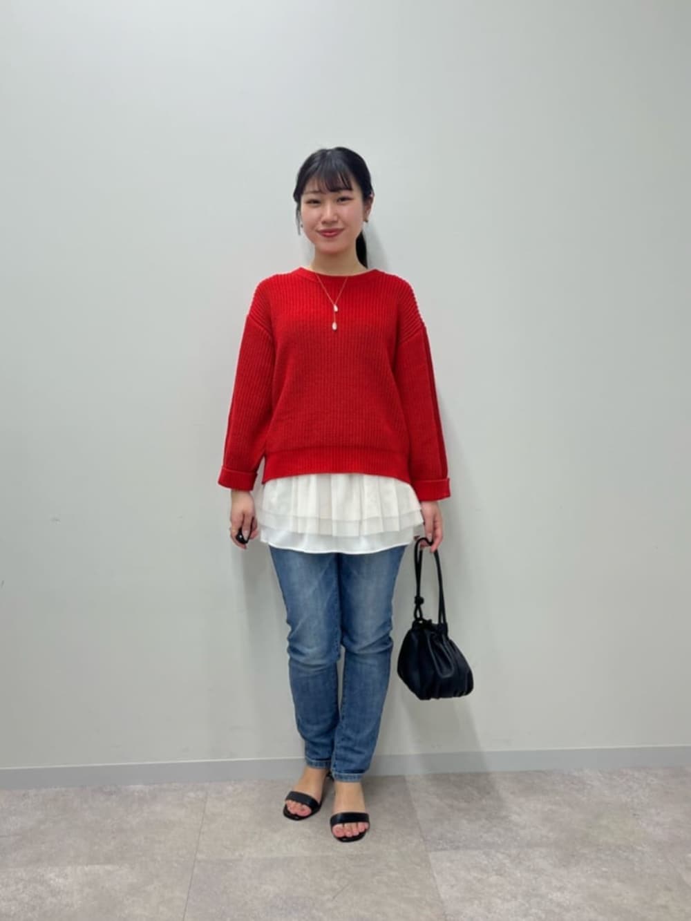 ブルー系のデニムパンツ、ホワイト系のタンクトップ、レッド系のニット/セーターを着用したレディースの冬コーディネートの2枚目の写真